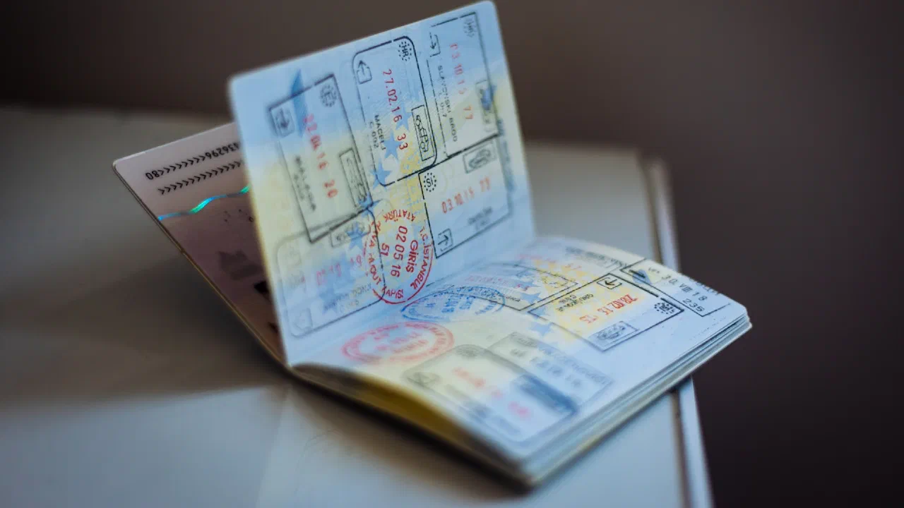 An open passport covered in ink entry and exit stamps, lying on a table