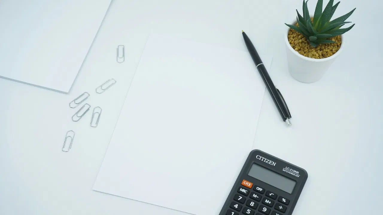 A black calculator and a black pen on a sheet of white paper